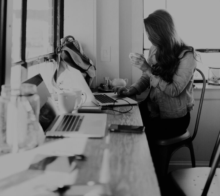 Woman at computer typing with coffee in hand