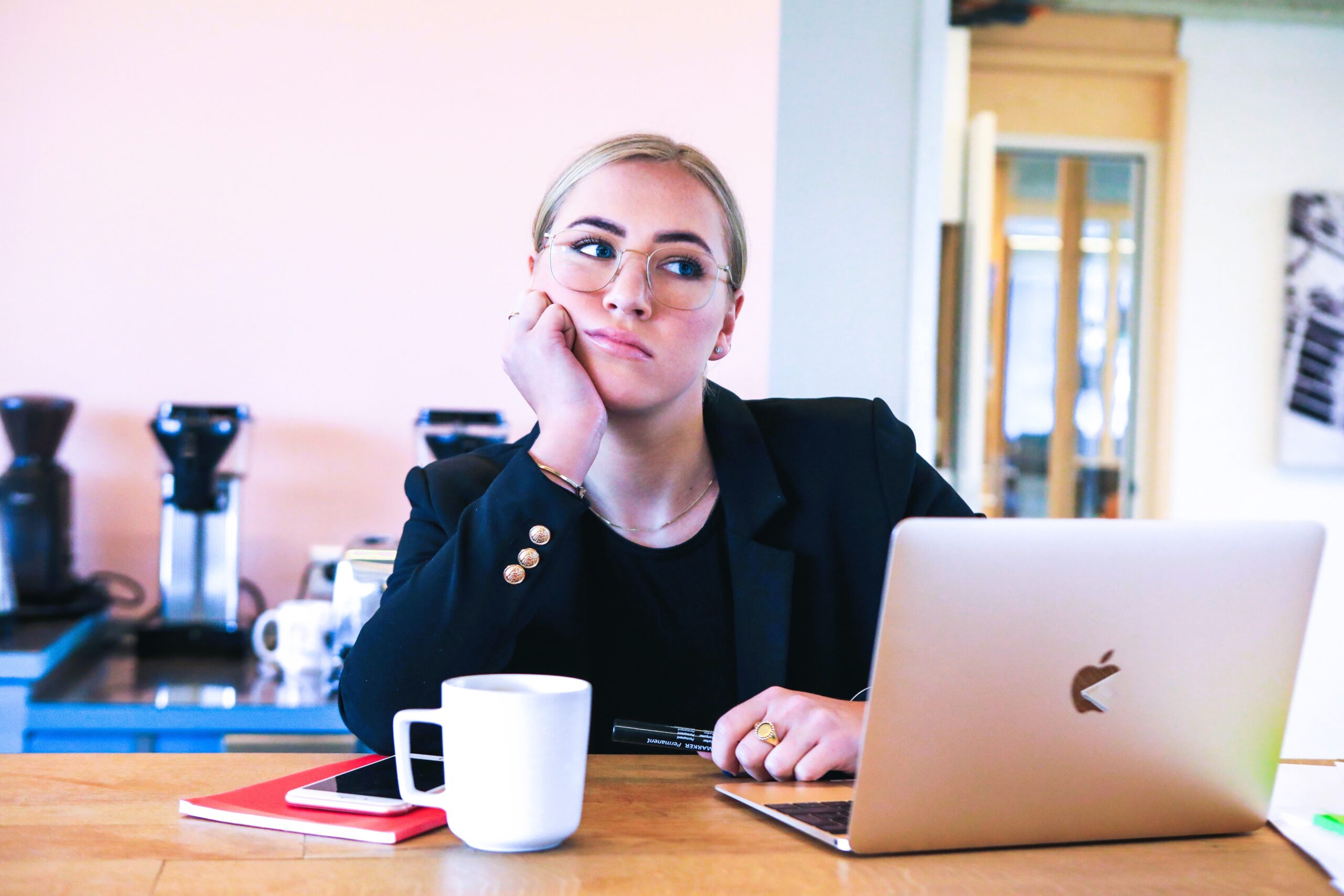 sad woman sitting at desk with face propped up with hand