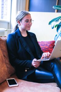 smiling woman sitting on couch with computer on lap